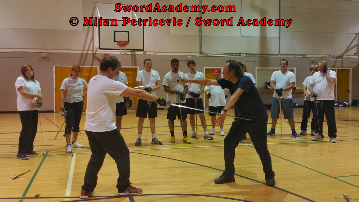 Milan demonstrates during an indoor class in front of Sword Academy students rapier exercise / drill using hand parry and thrust from Terza inspired by historical sources from the Italian renaissance tradition, part of Sword Academy HEMA / WMA / Martial Arts curriculum.