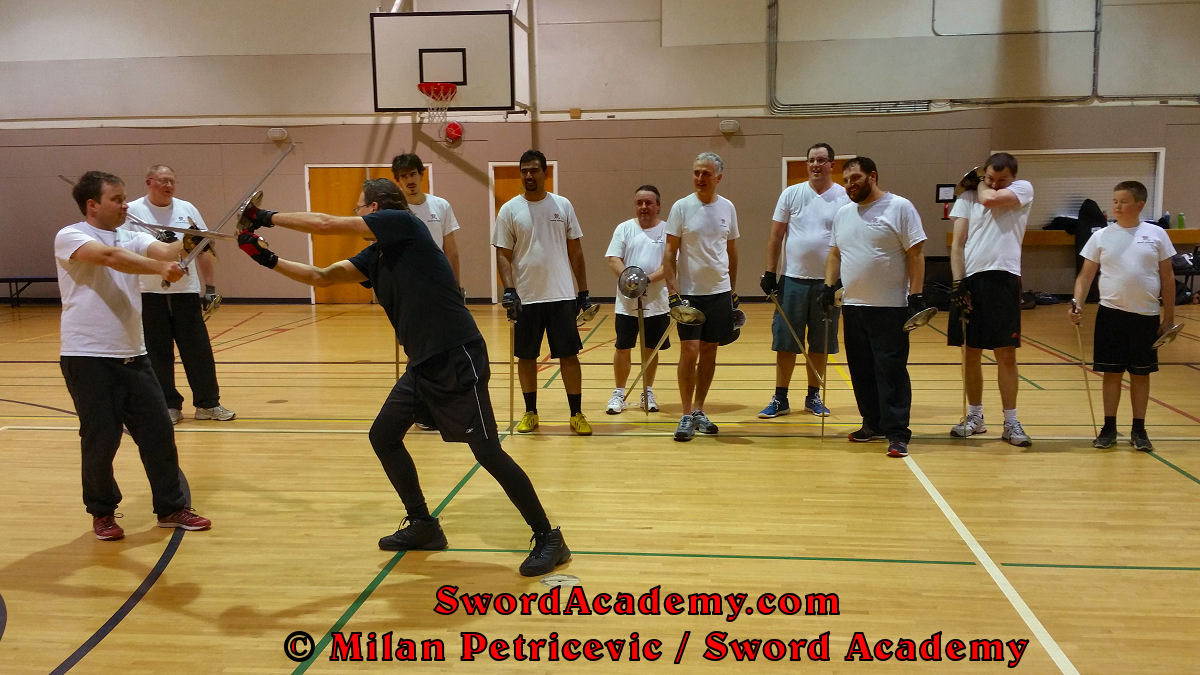 Milan demonstrates during an indoor class in front of Sword Academy students sword and buckler exercise / drill using a short edge cut from the weak side inspired by historical sources from the German medieval and renaissance tradition, part of Sword Academy HEMA / WMA / Martial Arts curriculum.