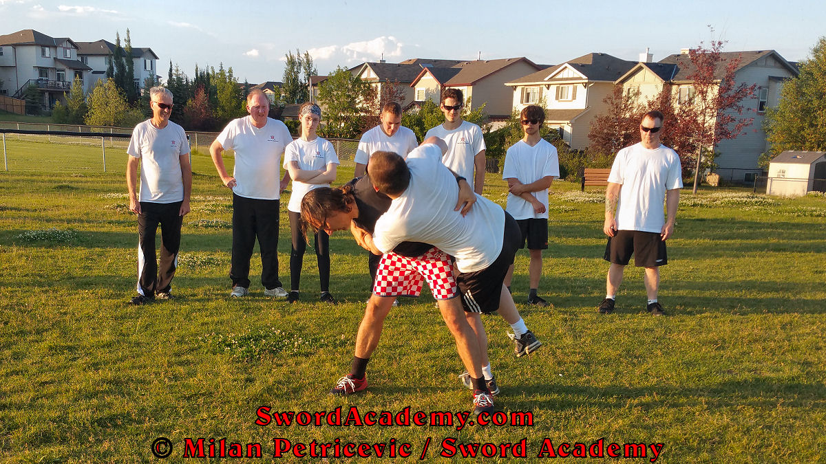 Milan demonstrates during an outdoor class in front of Sword Academy students wrestling exercise / drill using a throw from the second horizontal stance inspired by historical sources from the German medieval tradition, part of Sword Academy HEMA / WMA / Martial Arts curriculum.